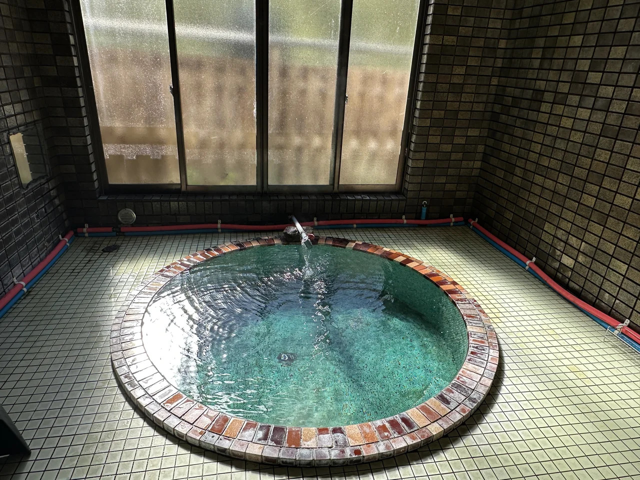 丸乃荘の男湯。円形の浴槽に源泉が満ちています